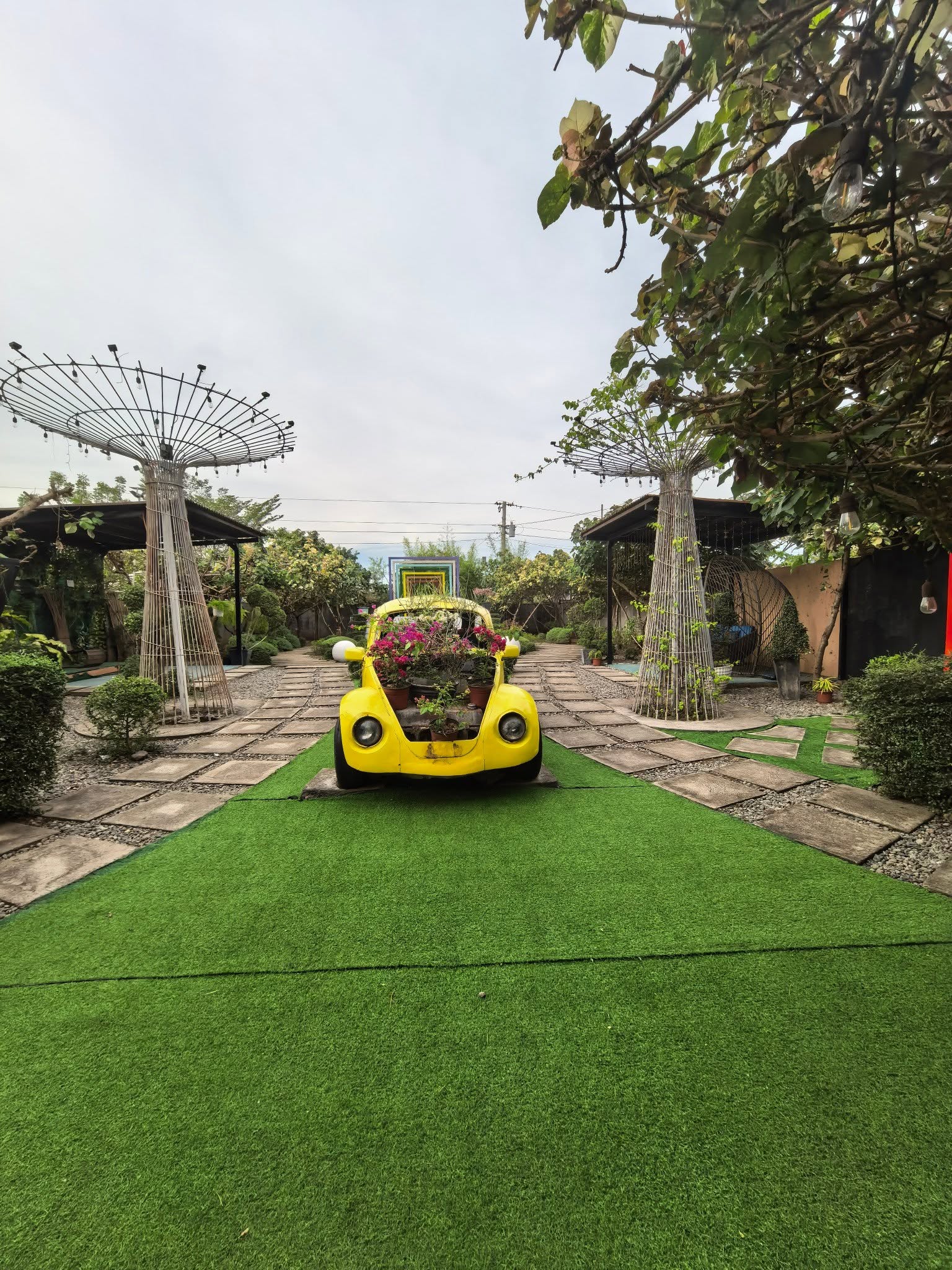 Yellow car planter centered between garden paths at D’ Garden at Calatao