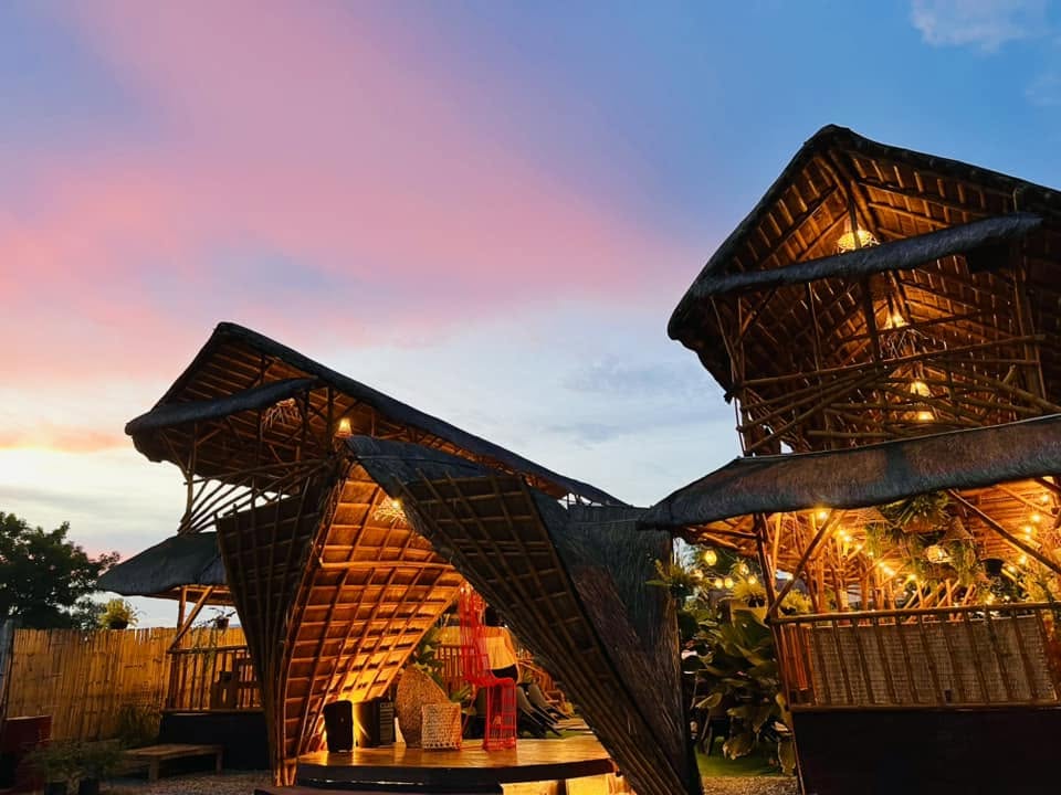 Bamboo structures beneath a pink evening sky at D’ Garden at Calatao