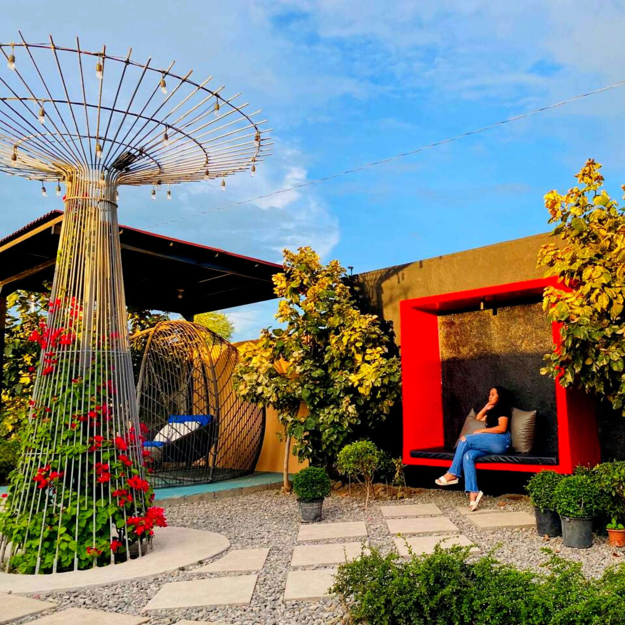Garden photo spots with a hanging chair and red framed seat at D’ Garden at Calatao