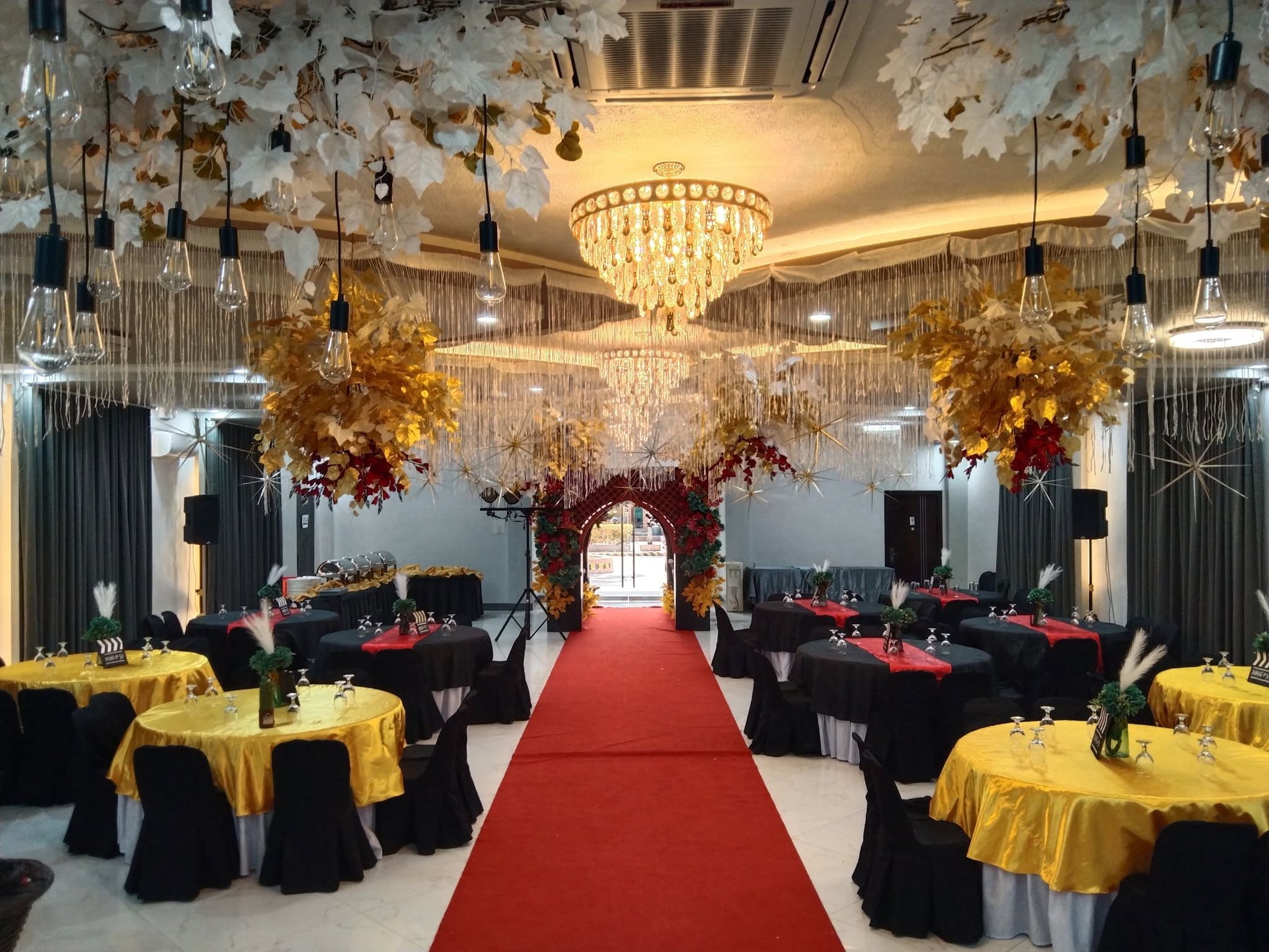 Convention hall prepared with round tables, floral decorations, and a red aisle