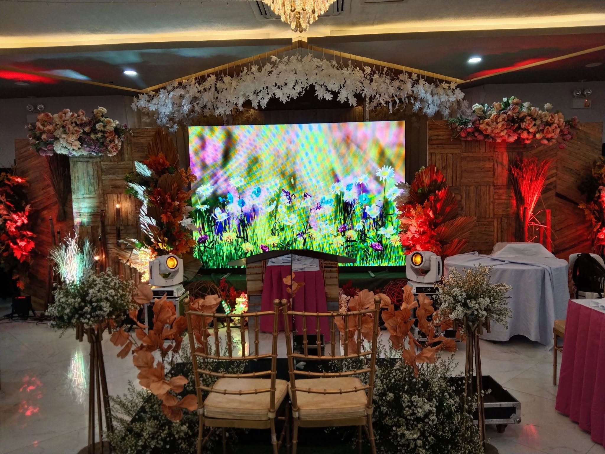 Event stage with floral decorations, lighting, and a large display