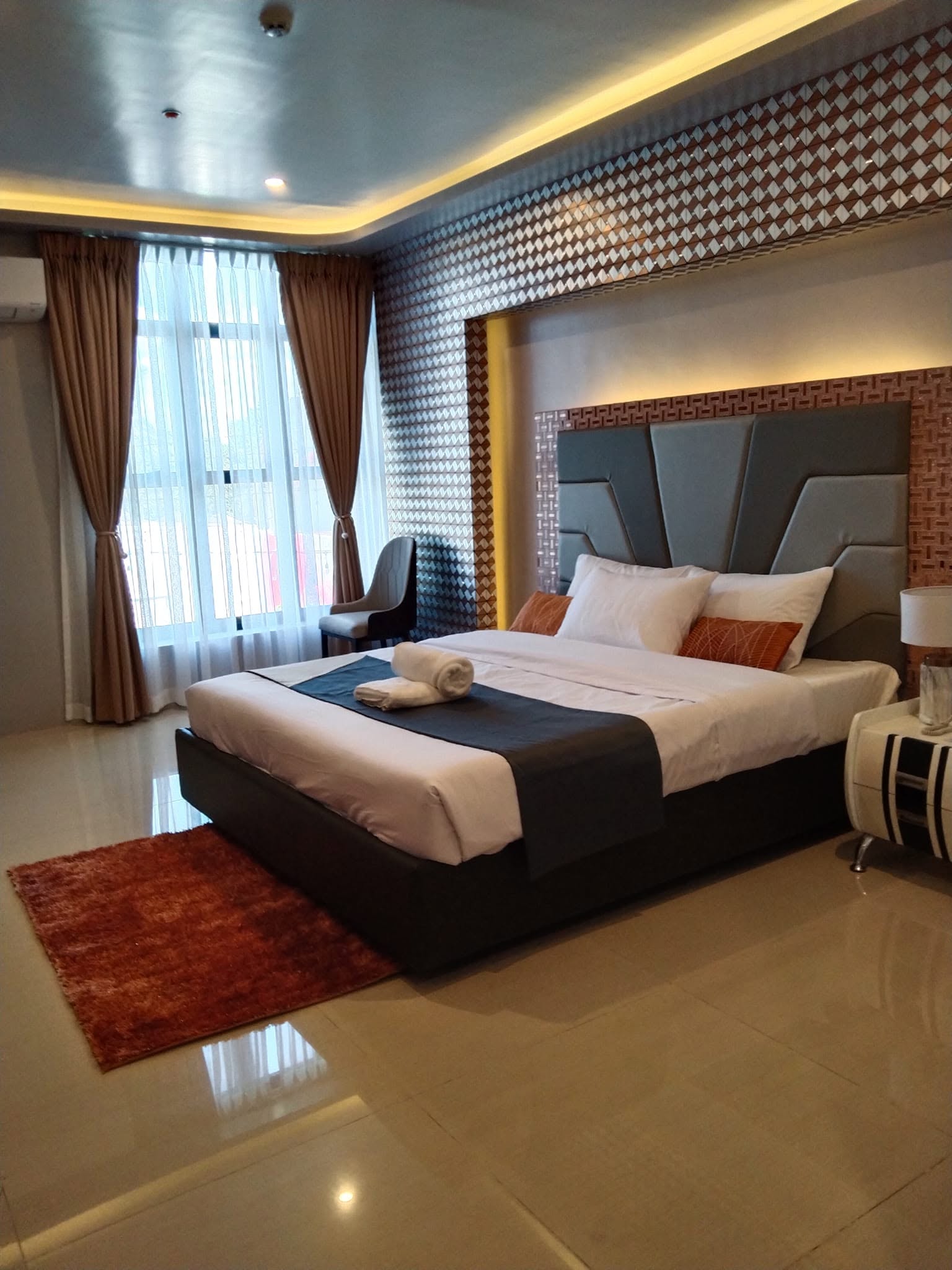 Queen-bed hotel room with warm lighting and large windows