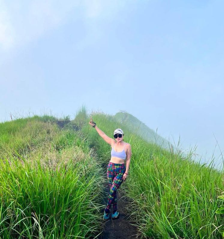 Irene Tan standing on a grassy mountain trail
