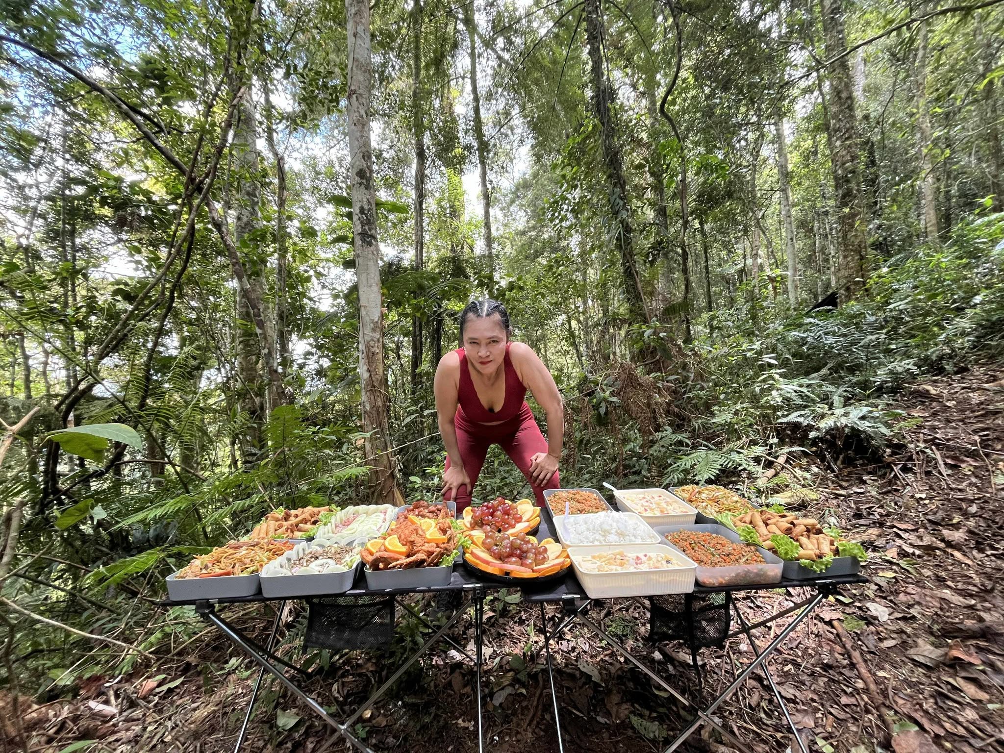 Irene Tan beside an outdoor food table in a forest