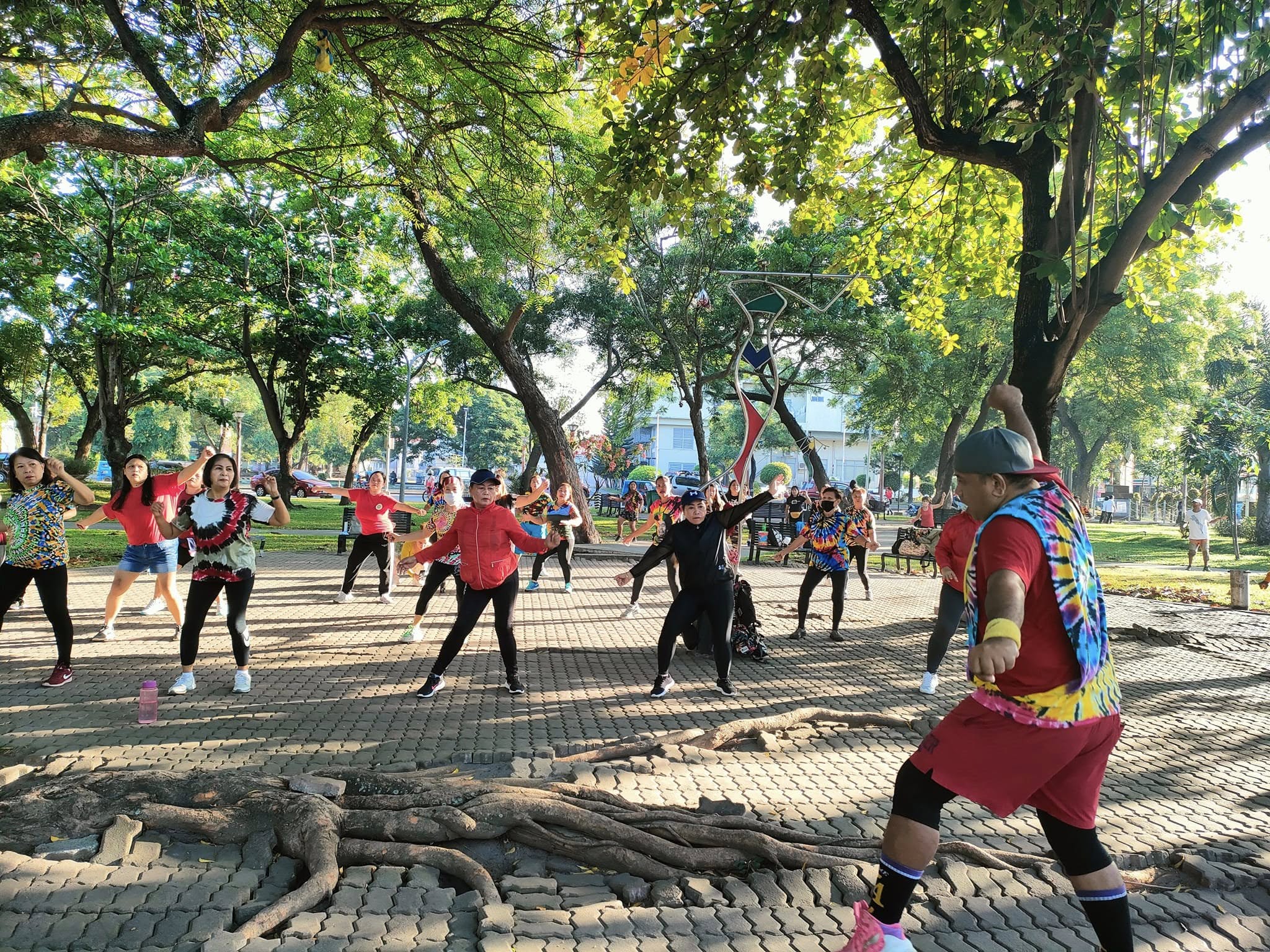 Group exercise session under the trees at Plaza Heneral Santos