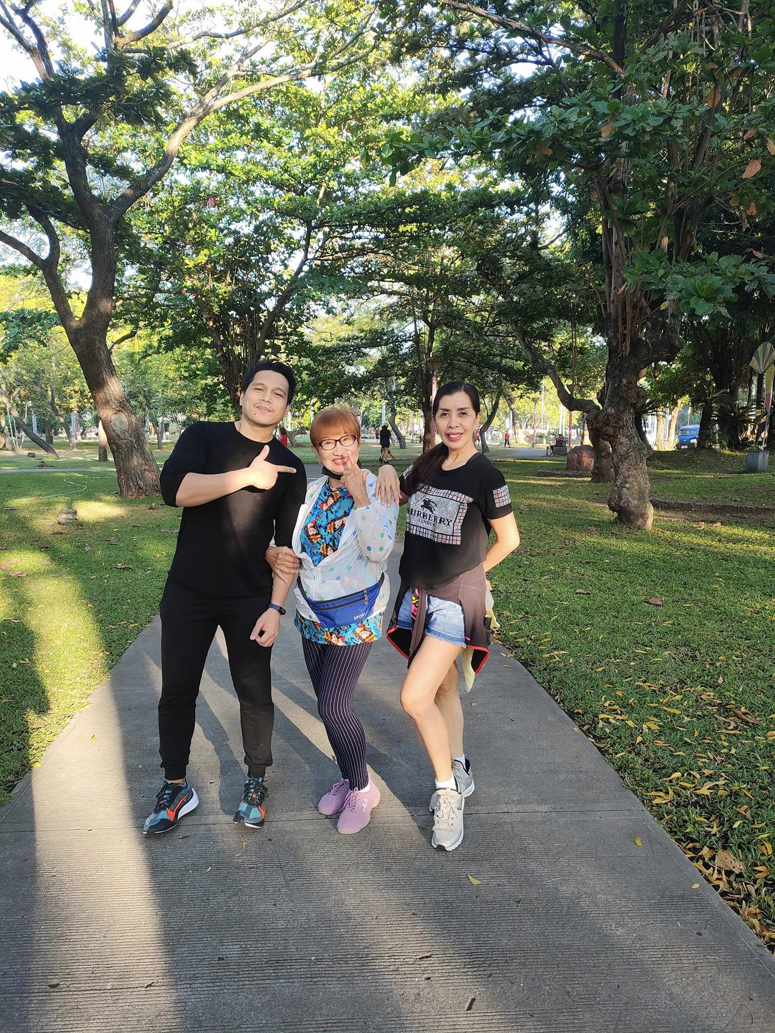 Visitors posing along a tree-lined walkway at Plaza Heneral Santos