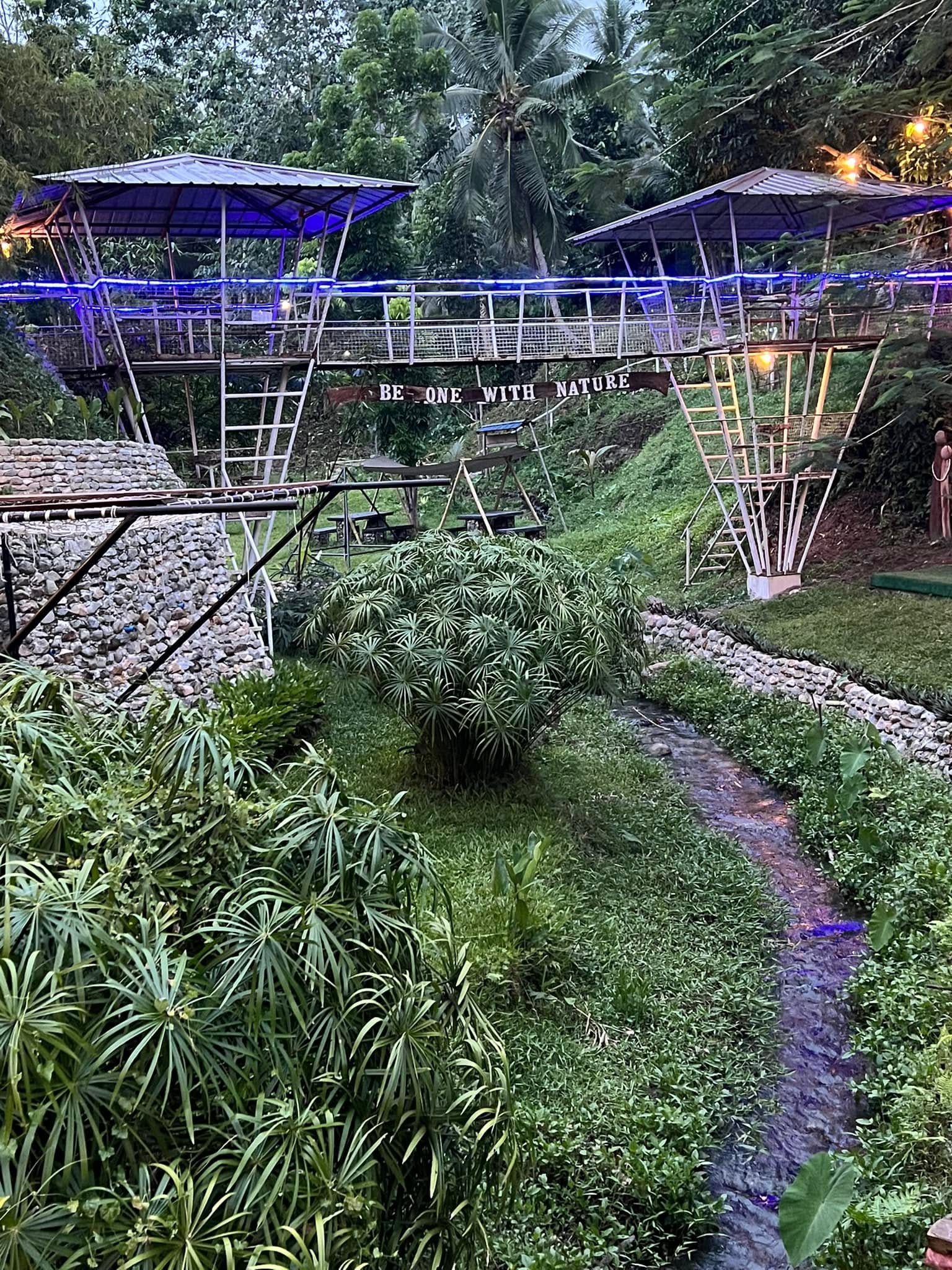 Elevated walkway and shelters above a leafy creek