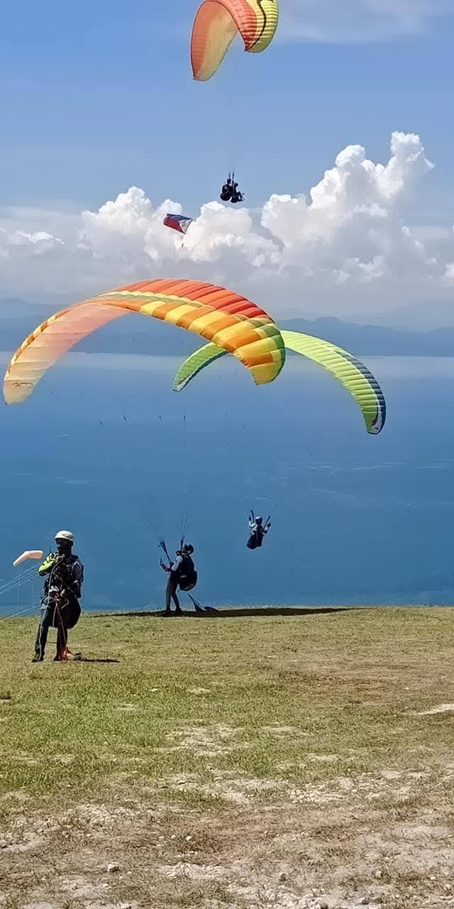 Multiple paragliders preparing and flying from the launch area