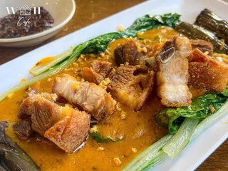Cooked meat pieces with greens in a brown sauce
