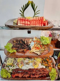 Tiered spread with fruit, grilled foods, fish, rice, shellfish, and vegetables